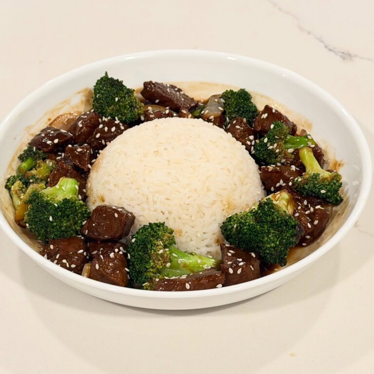 Homemade broccoli beef with cubed ribeye simmered in a savory soy ginger sauce with broccoli, onions, sesame seeds, and served over jasmine rice.