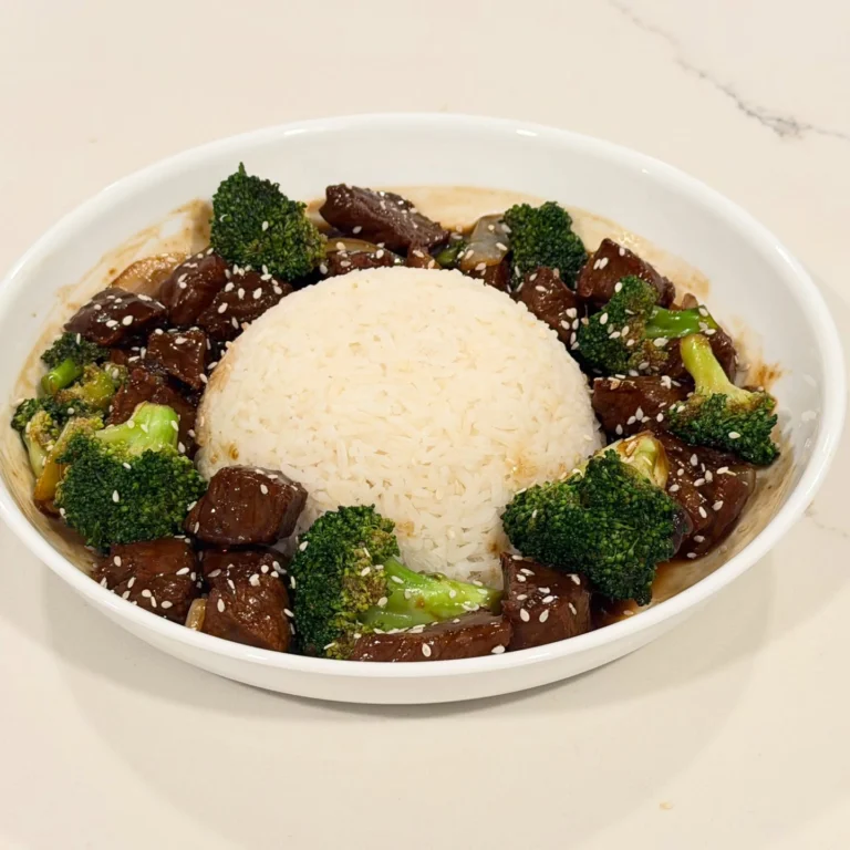 Homemade broccoli beef with cubed ribeye simmered in a savory soy ginger sauce with broccoli, onions, sesame seeds, and served over jasmine rice.