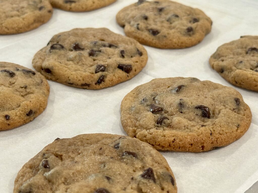 Brown Butter Chocolate Chip Cookies cooling on parchment paper with golden edges and melty chocolate chips.