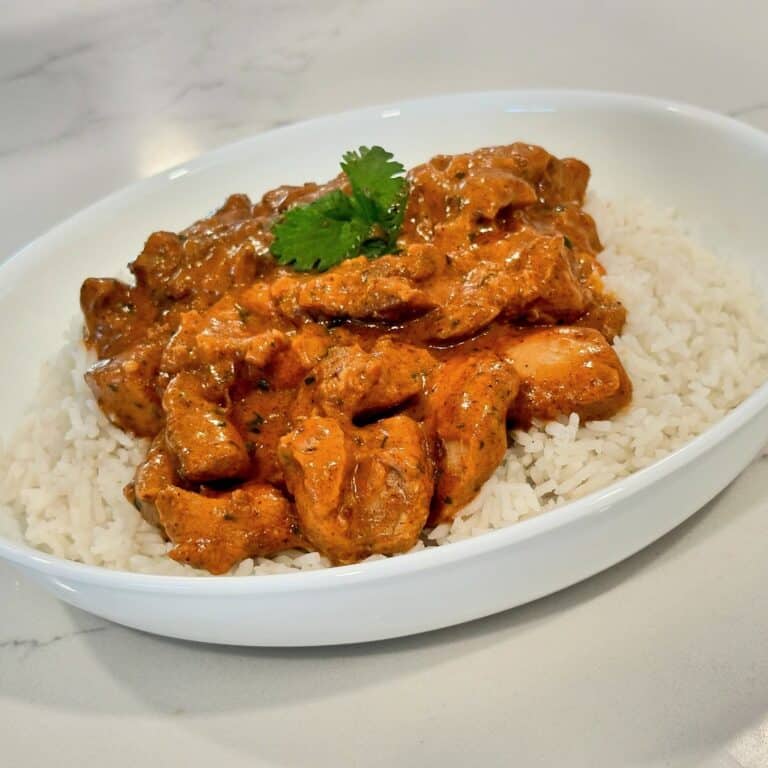 Homemade butter chicken served over basmati rice with rich creamy tomato sauce and fresh cilantro.