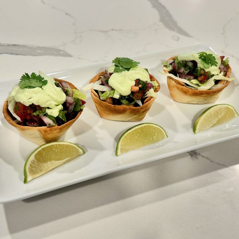Cantina chicken taco cups filled with seasoned chicken, black beans, lettuce, pico de gallo, avocado crema, cilantro, and lime wedges.