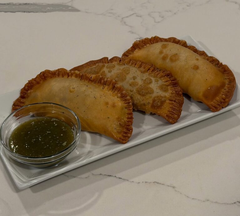 Golden fried cheesesteak empanadas filled with shaved steak, peppers, onions, mushrooms, garlic, smoked provolone, gruyère, and mozzarella served with green dipping sauce.