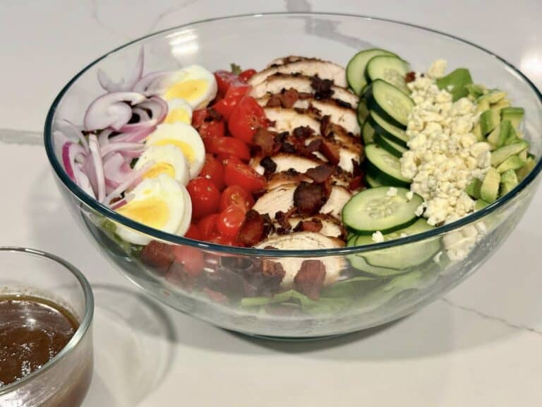 Homemade Cobb salad with grilled chicken, bacon, avocado, cucumber, tomatoes, egg, red onion, blue cheese, and balsamic dressing.