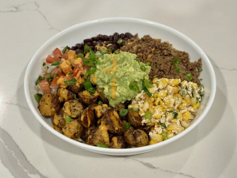 Fiesta Potato Taco Bowl with crispy baby gold potatoes, taco meat, black beans, homemade elote salad, pico de gallo, guacamole, and chipotle crema.