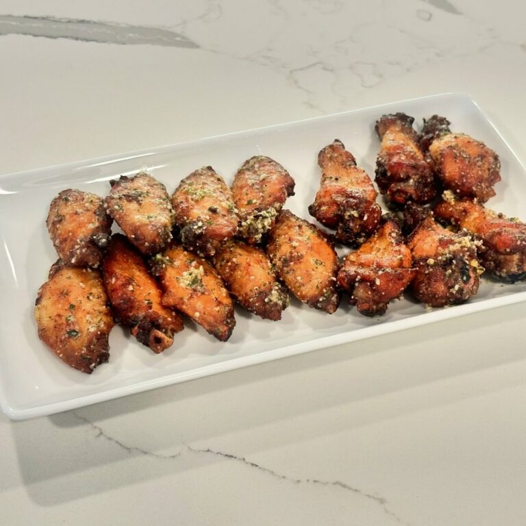 Crispy garlic Parmesan chicken wings topped with grated Parmesan and parsley on a white platter.