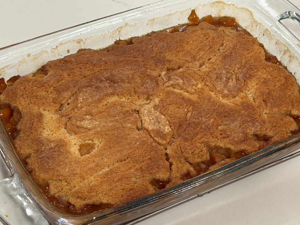 Homemade peach cobbler baked until golden and finished with caramel drizzle and French vanilla ice cream.