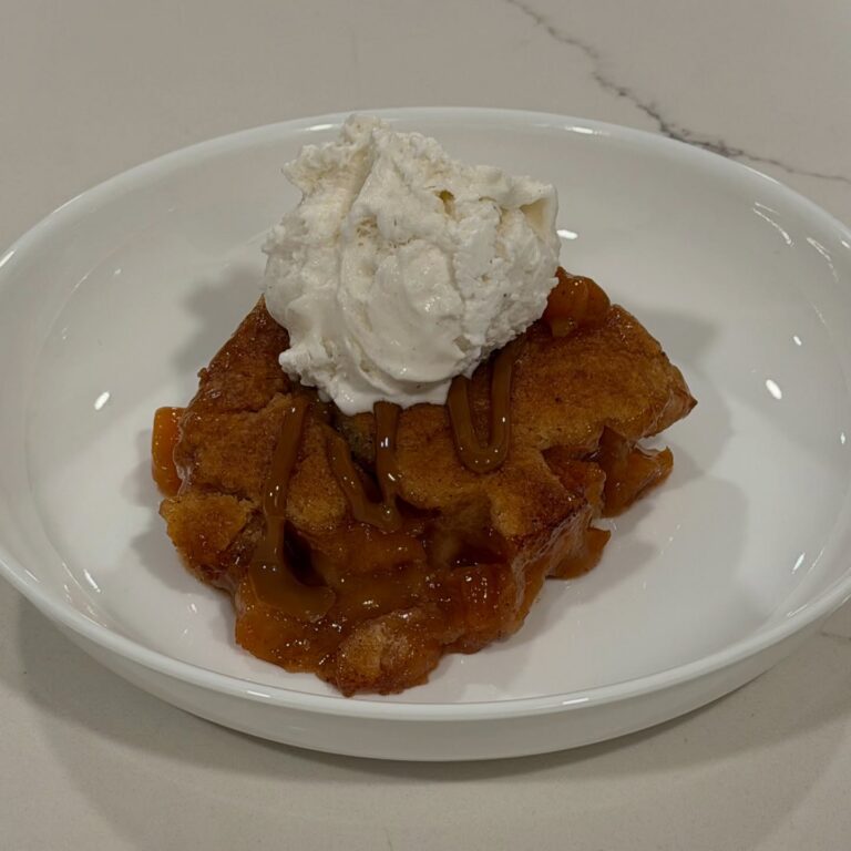 Homemade peach cobbler baked until golden and finished with caramel drizzle and French vanilla ice cream.