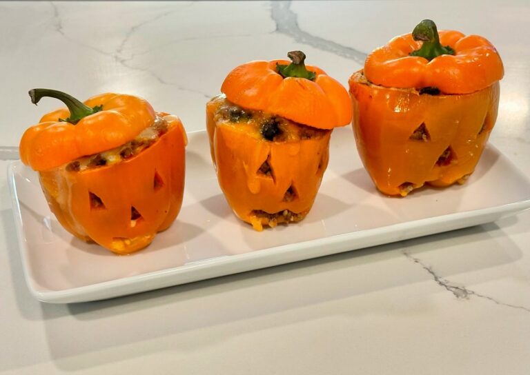Halloween stuffed orange bell peppers carved like jack o’ lanterns and filled with savory ground beef, Spanish rice, and melted cheese.
