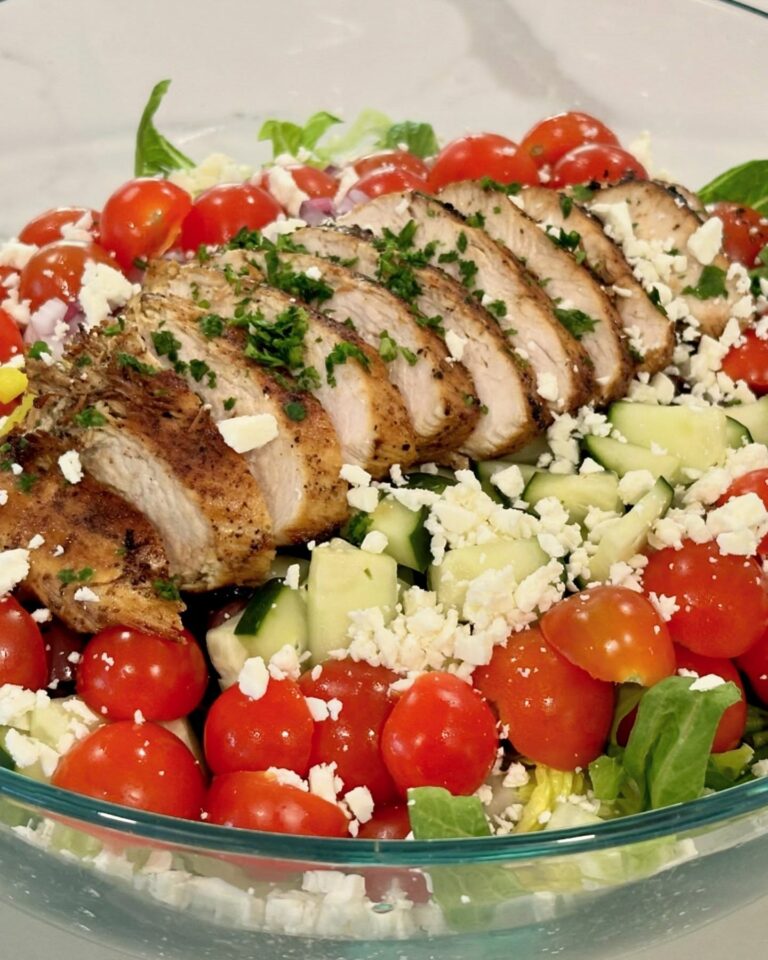 Lemon chicken Greek salad with sliced chicken breast, romaine lettuce, cucumber, cherry tomatoes, red onion, olives, banana peppers, feta cheese, and parsley.