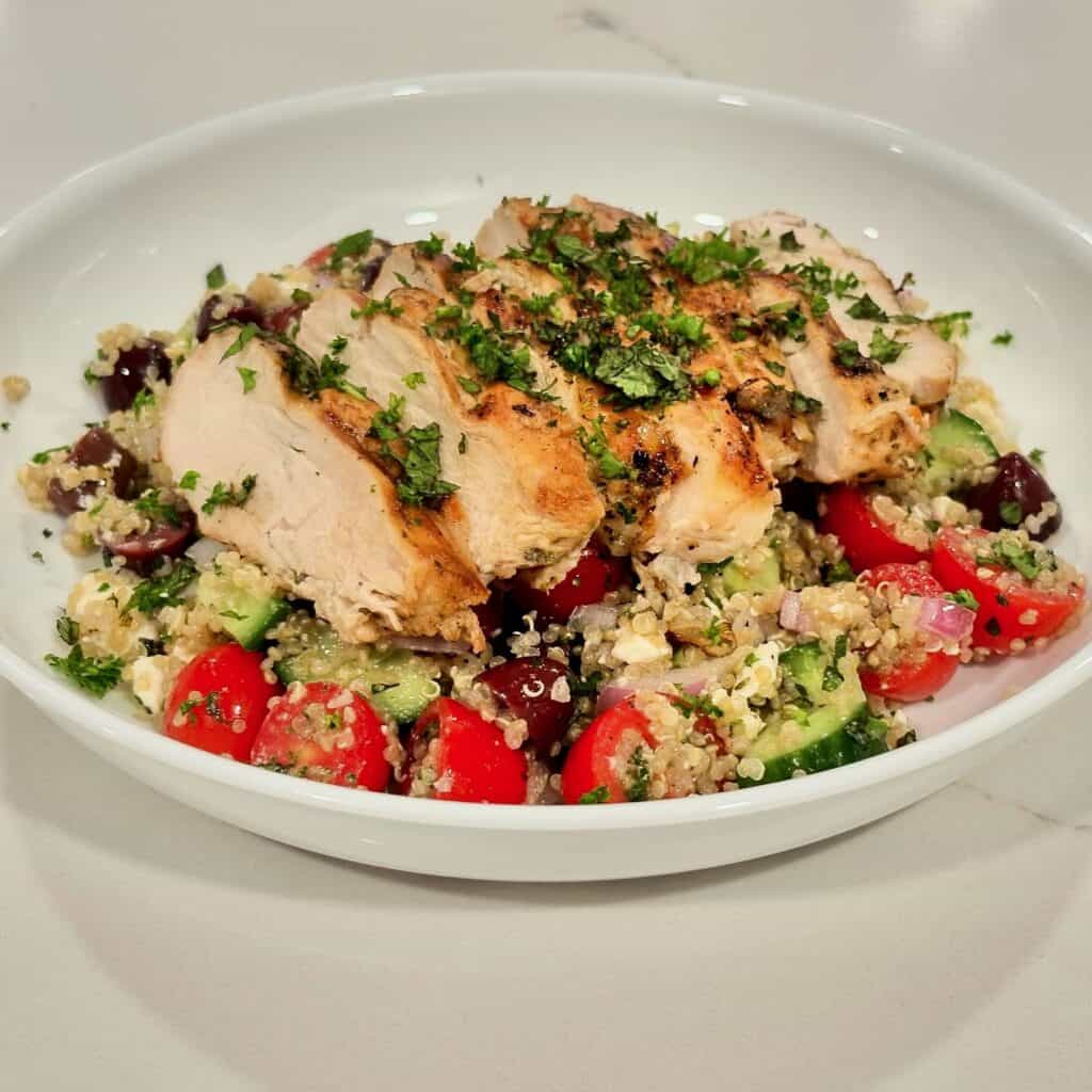 Mediterranean grilled chicken served over quinoa salad with cucumber, tomatoes, olives, red onion, and fresh herbs.
