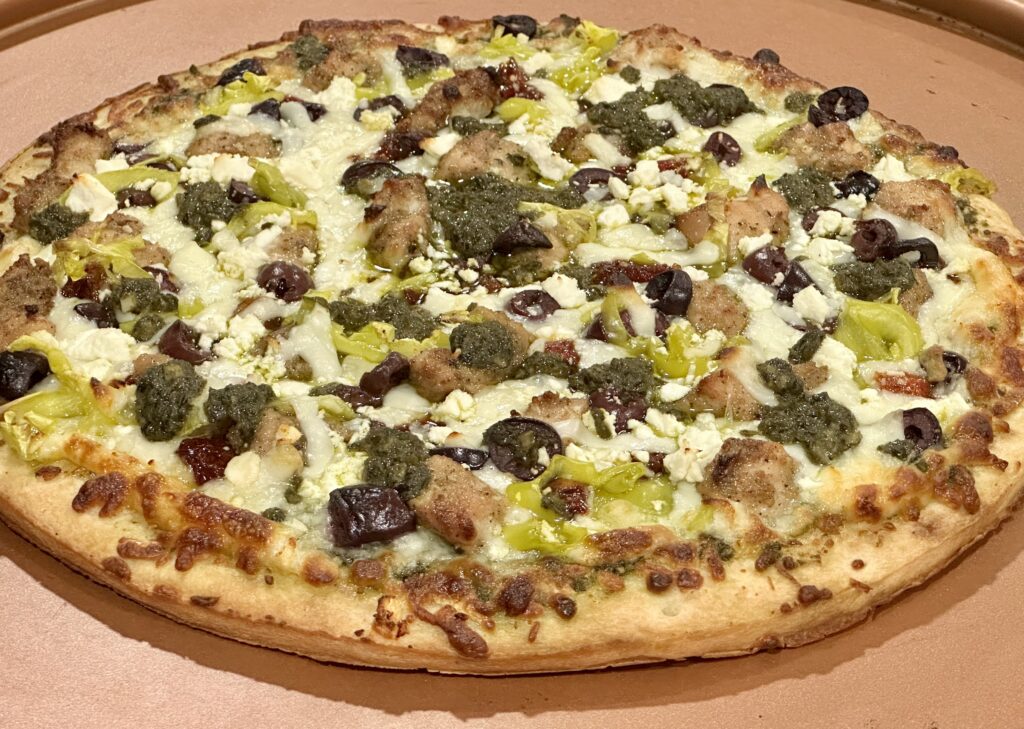 Mediterranean Pizza Homemade Mediterranean pizza with pesto sauce, Greek-seasoned chicken, feta cheese, kalamata olives, pepperoncini, and sun-dried tomatoes.