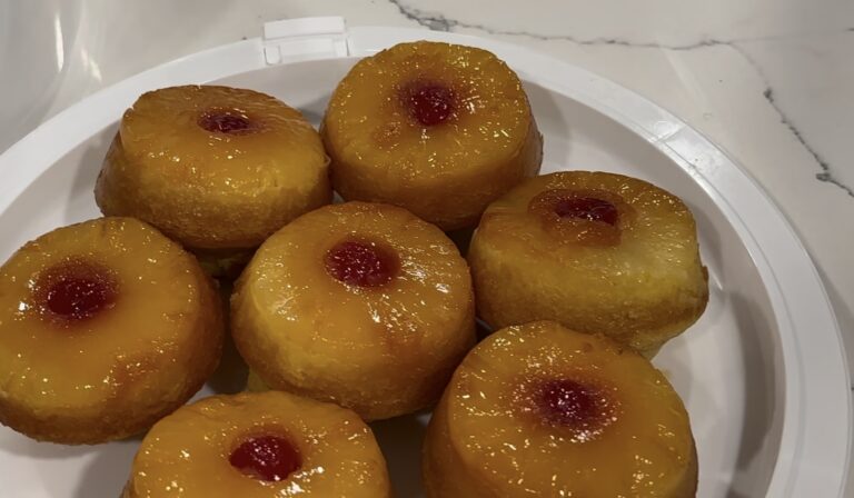 Mini pineapple upside down cake with caramelized pineapple and cherry on a white plate.