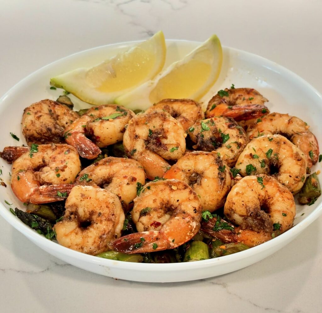 One-pan garlic butter shrimp served with asparagus and lemon wedges.