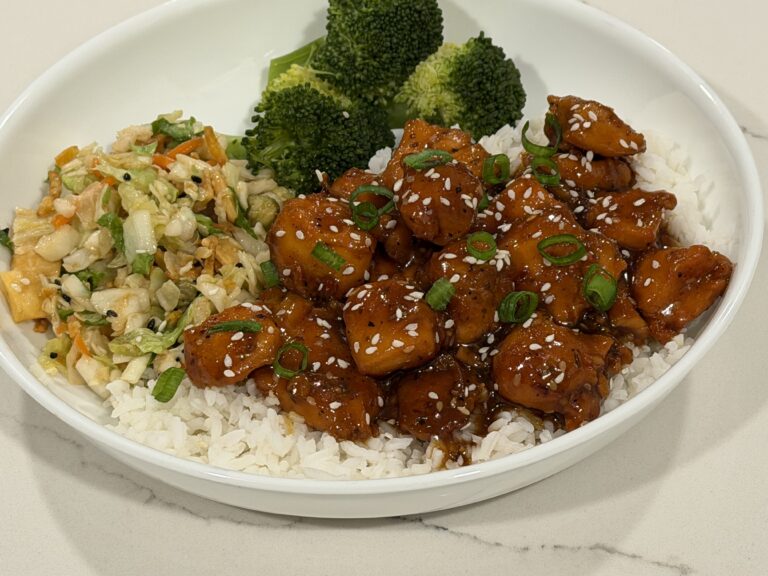 Orange Chicken Rice Bowl with jasmine rice, steamed broccoli, Asian slaw, sesame seeds, and green onions.