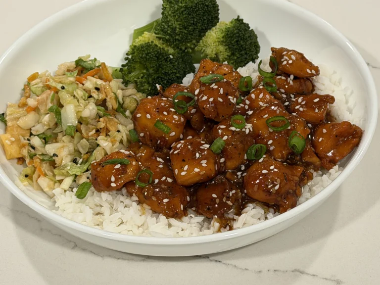 Orange Chicken Rice Bowl with jasmine rice, steamed broccoli, Asian slaw, sesame seeds, and green onions.