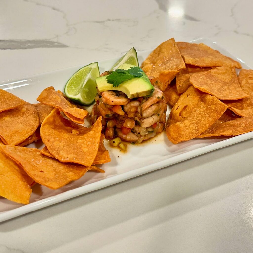 Fresh shrimp ceviche with avocado lime and tortilla chips plated on white serving tray by Reynaldo’s Cocina