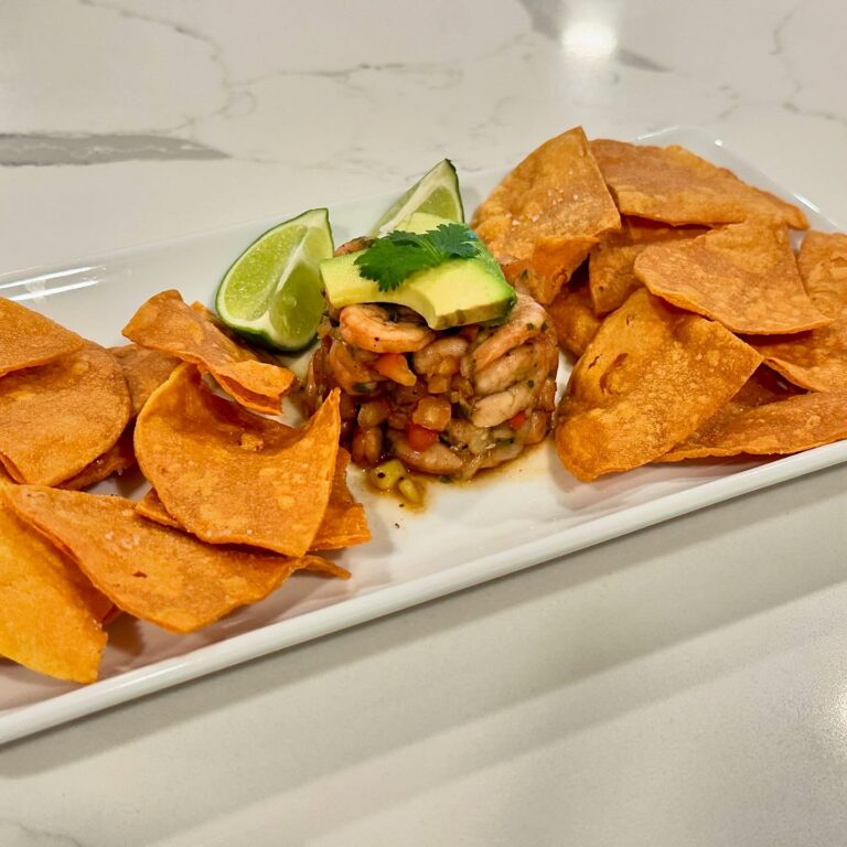 Fresh shrimp ceviche with avocado lime and tortilla chips plated on white serving tray by Reynaldo’s Cocina