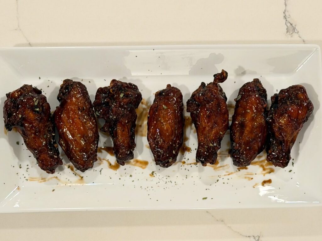 Homemade sticky soy garlic chicken wings with crispy fried skin brushed with a glossy garlic soy glaze and finished with herbs.