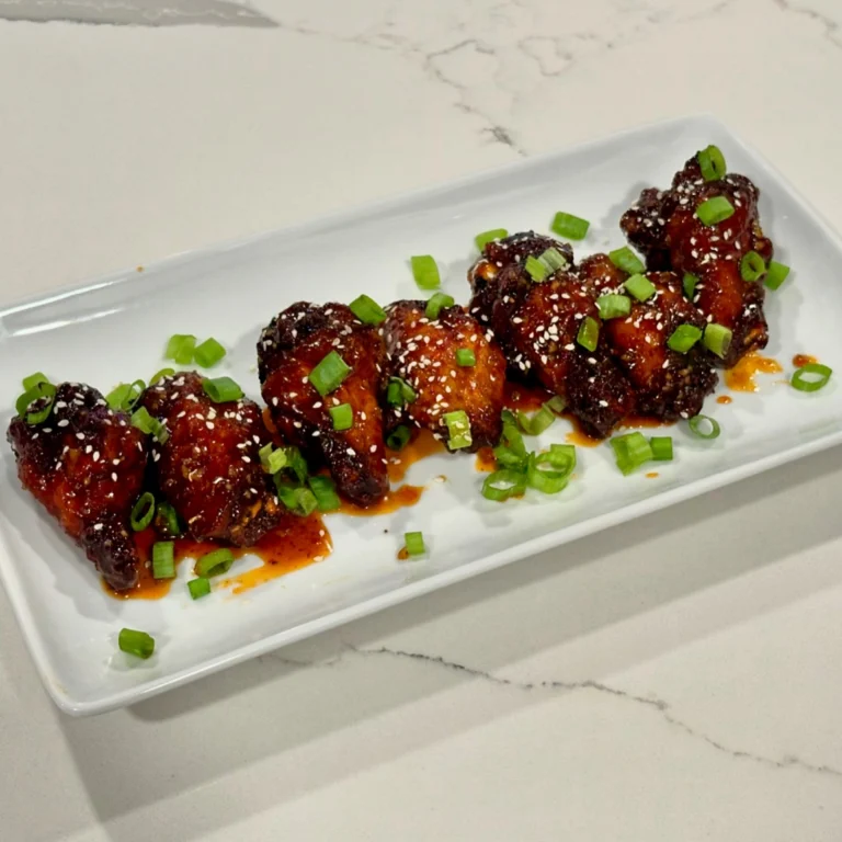Spicy honey garlic chicken wings glazed with sauce and topped with green onions and sesame seeds.