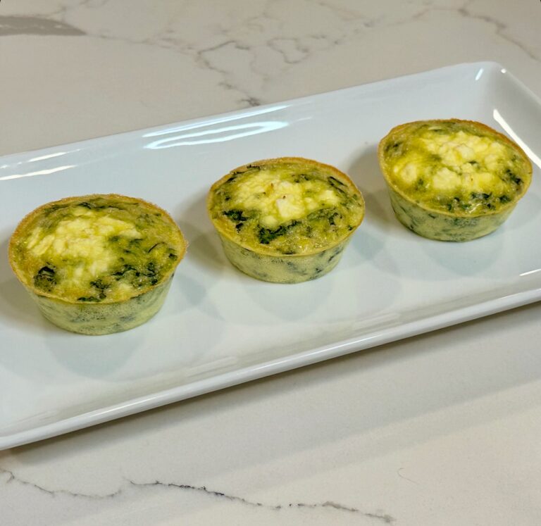 Spinach and feta egg cups baked in muffin tins and served on a white platter.