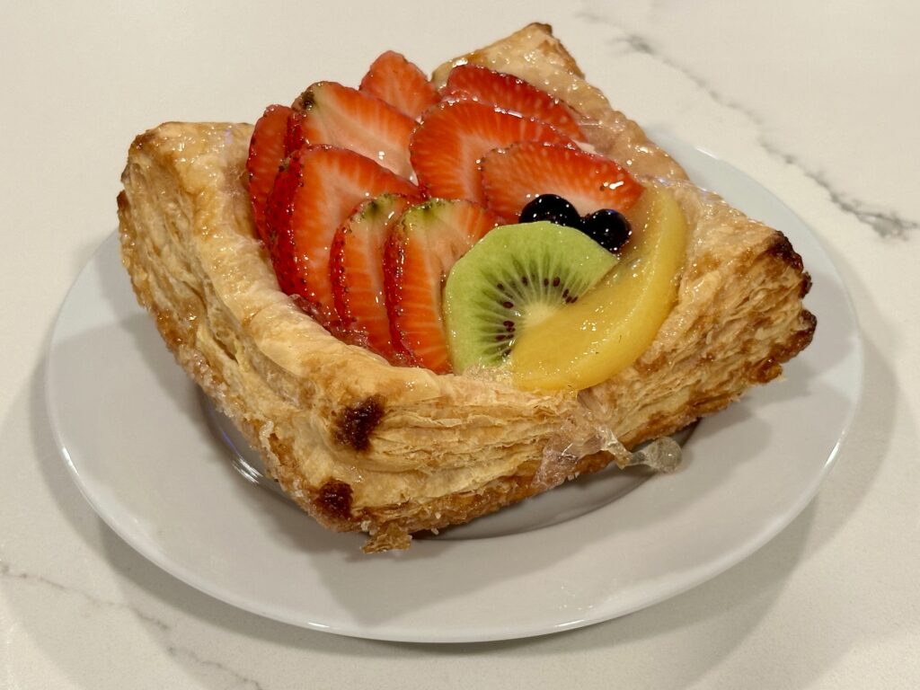 Tropical Fruit Tart Tropical Fruit Tart made with puff pastry, vanilla custard, strawberries, kiwi, peaches, blueberries, and fruit glaze.